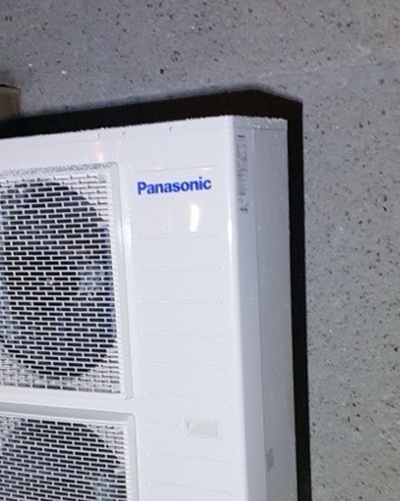 Jednostka zewnętrzna pompy ciepła Panasonic Aquarea na bloczkach przy elewacji budynku — montaż Instal-Home